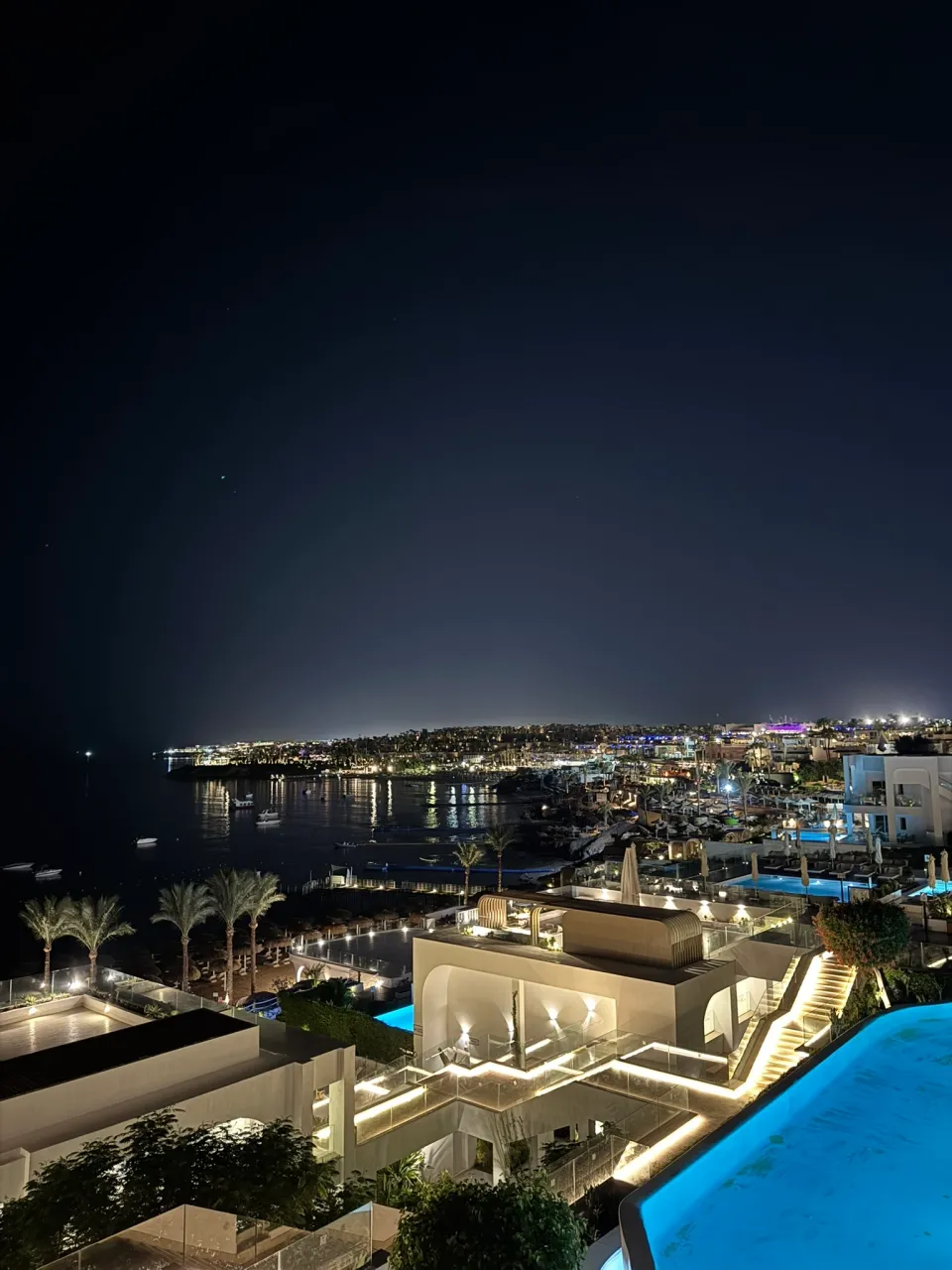 ライトアップされたホワイトヒルズの建物とプール、海辺の夜景