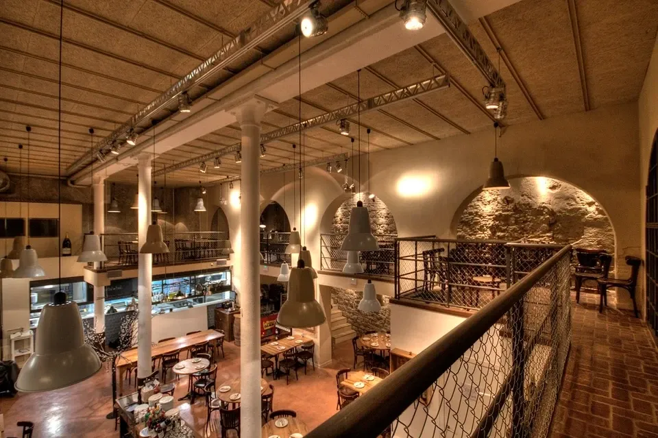 Bodega La Puntualの店内。吹き抜けに吊り照明。上階の回廊と下階の客席。