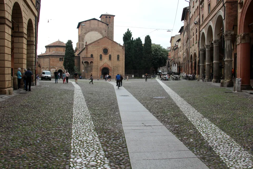 The Santo Stefano church complex beyond a cobbled square and arcades in Bologna