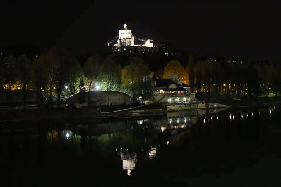 The illuminated church on Monte dei Cappuccini reflected in the Po River at night