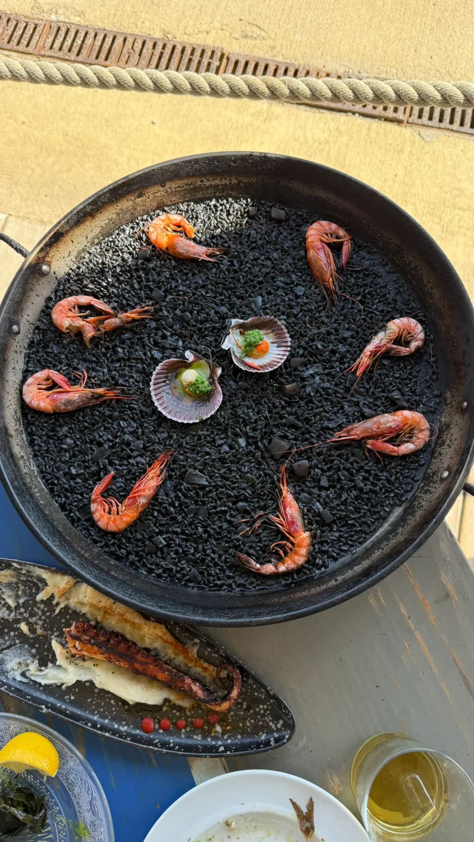 Xiringuito Escribàの大きな鍋に入った黒い米料理と魚介