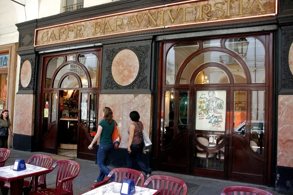 Curved wooden doors and ornate dark trim on a café façade along Via Po in Turin
