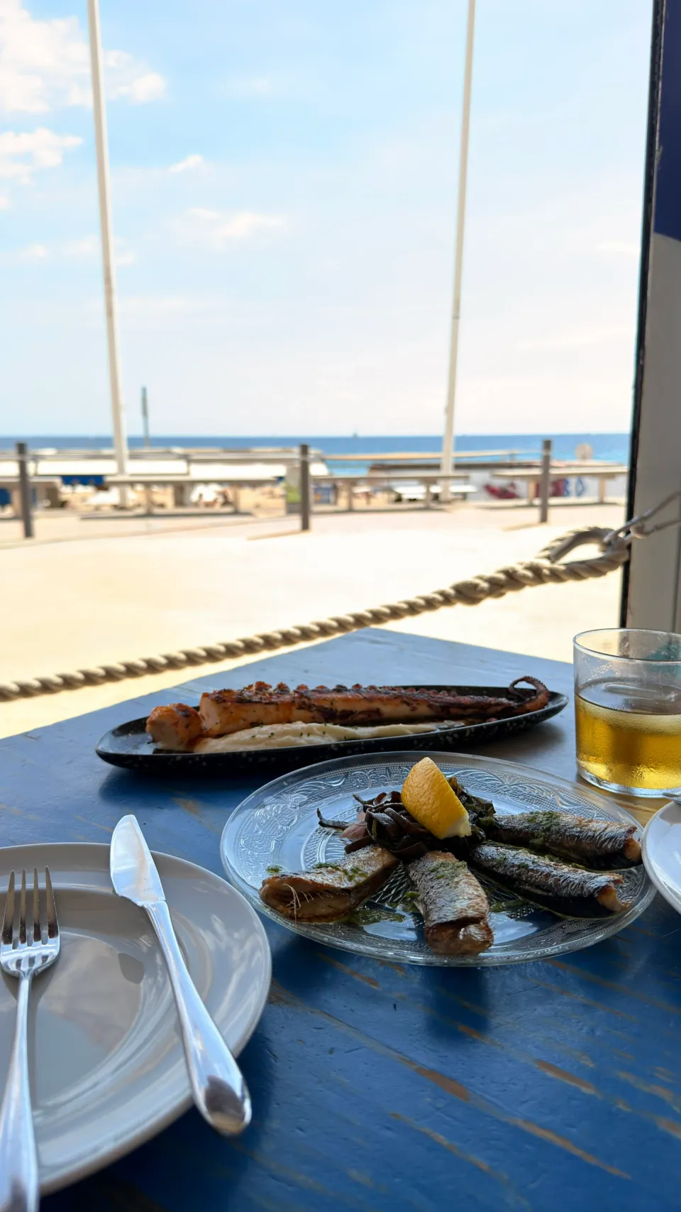 海を望むXiringuito Escribàのテーブルに魚介料理と飲み物