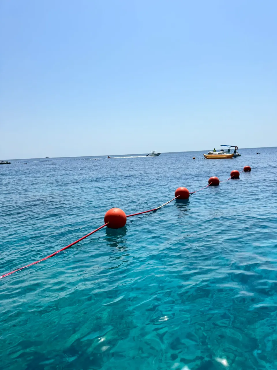 透き通った青い水面と、沖へ続く赤いブイ