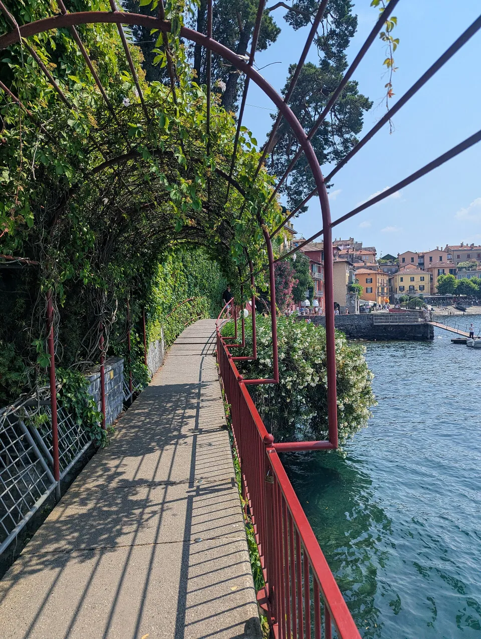 Red handrails and vine-covered arches above the narrow Passeggiata degli Innamorati beside Lake Como in Varenna