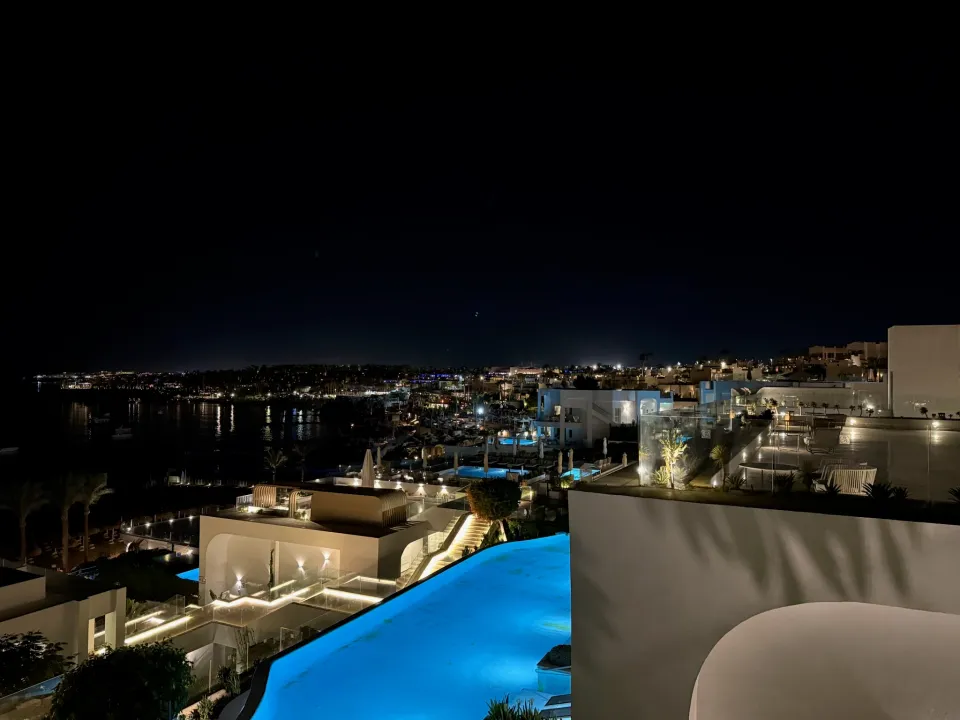青くライトアップされたプールと海沿いのホテルの夜景