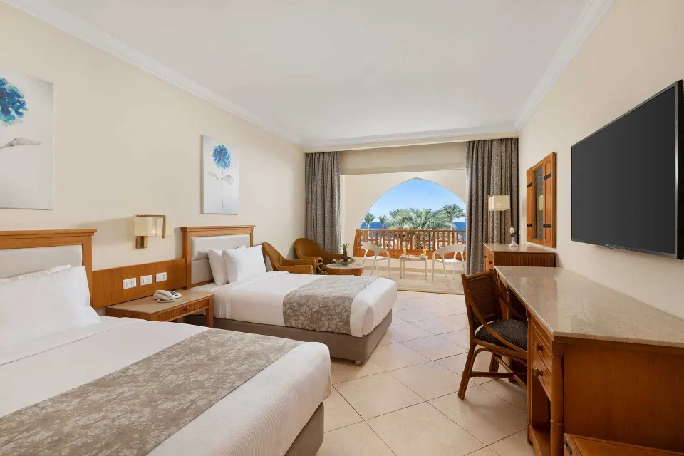 Royal GrandのSuperior Room Sea Viewの客室例。木の家具とツインベッド、アーチの先の海