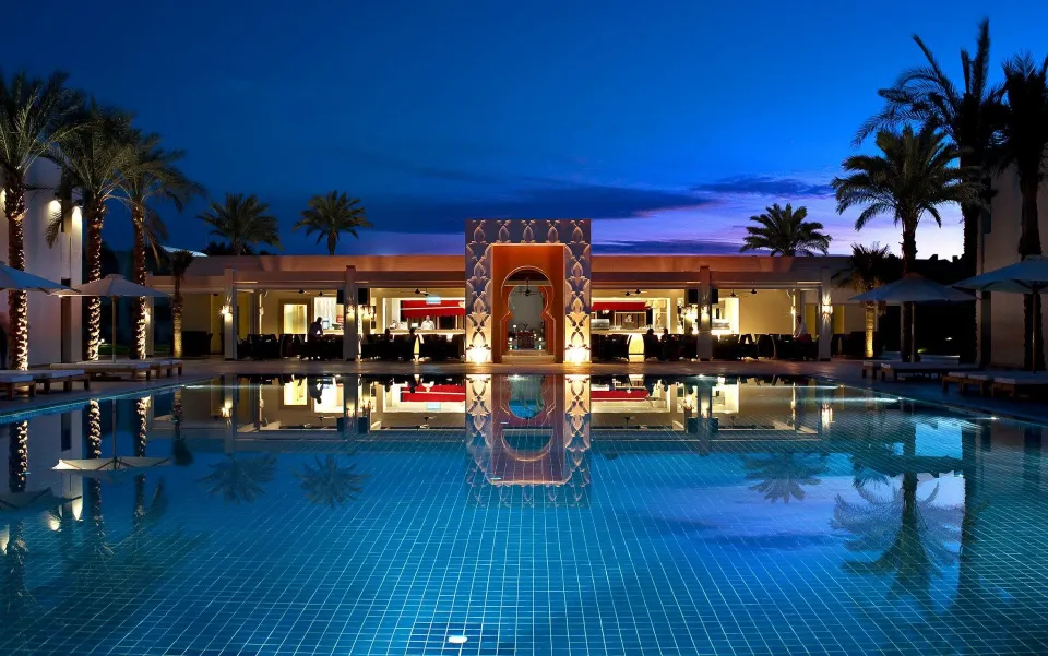 Sentido公式がLa Terrazzaの欄に掲載する夜の水辺。中央のアーチと食事の建物、ヤシの灯りが青いプールに映っている