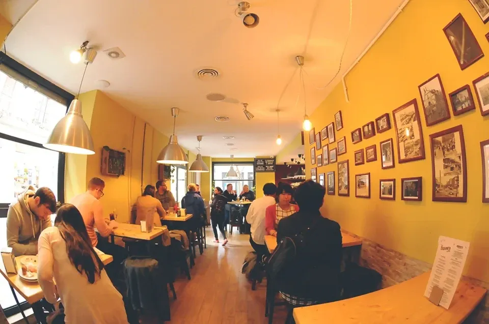 La Esquinita de Blaiの店内。黄色い壁のテーブル席と、奥へ続く中央の通路。